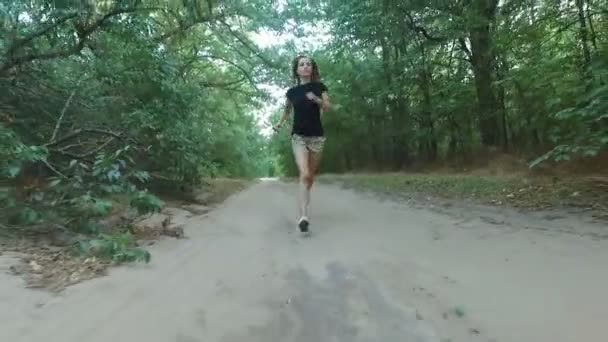 La fille court le long de la route forestière. Tirer sur le bourdonnement 