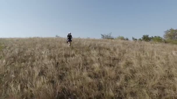 A girl with a backpack on her shoulders runs away from a steep slope. — Stock Video