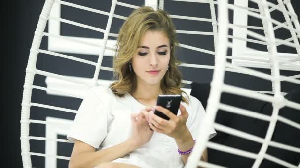 Het blonde meisje gebruikt haar smartphone. — Stockvideo