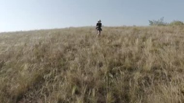 Bir sırt çantası onun omuzlarında bir kızla uzak dik bir yamaç çalışır. Ağır çekim