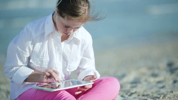 Девушка с синдромом Дауна играет на сенсорном экране на пляже — стоковое видео
