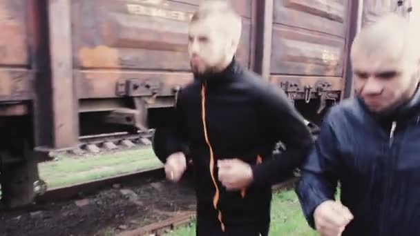 Male athletes running on railroad — Stock Video