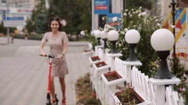 Güzel kız kaldırımda elektrikli scooter kullanıyor.