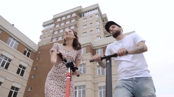 Pasangan berdiri di atas skuter listrik dan berbicara tembakan sudut rendah — Stok Video