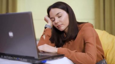 Yorgun kadın iş yerinde dizüstü bilgisayarın yanında uyuyor.