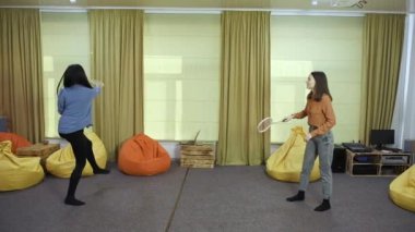 Mutlu kızlar birlikte ağır çekimde molalarda badminton oynarlar.