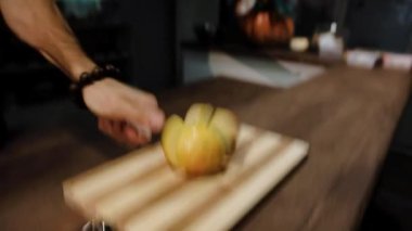 Aşçı keskin bıçağı indirir, sarı elmayı parçalara ayırır.