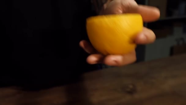 Muž s tetováním na paži hodí a chytí půl citronu — Stock video