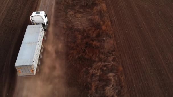 Le camion se déplace le long d'un chemin de terre parmi le champ labouré . — Video