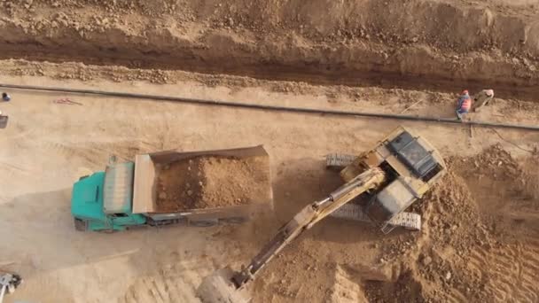 Εκσκαφέας φορτώνει χώμα στο φορτηγό ανέλκυσης, από πάνω προς τα κάτω εναέρια πλάνα — Αρχείο Βίντεο