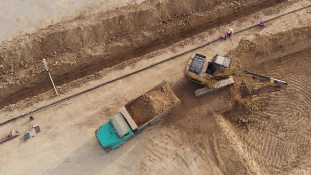 Grävmaskinen lastar lastbilen med jord. Flygbild. — Stockvideo