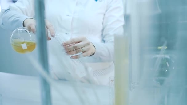 Lab technician pours a drink from a flask into a test tube. — ストック動画