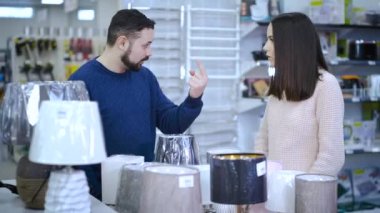Married couple swearing when choosing a small night lamp in a supermarket.