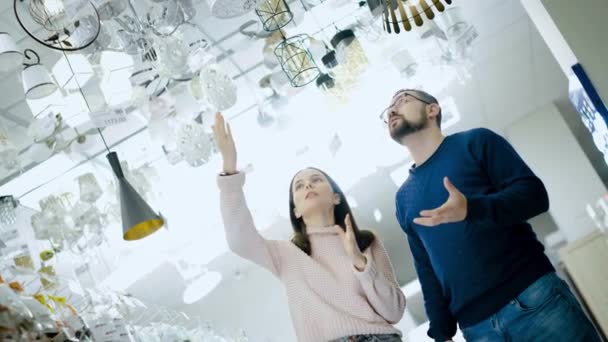 Mladý pár si vybere lampu v obchodě s elektrickým zbožím. — Stock video