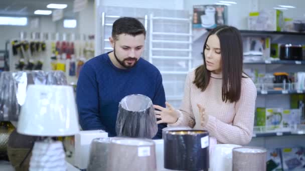 El tipo con la chica elegir una pequeña lámpara de noche en el supermercado — Vídeos de Stock