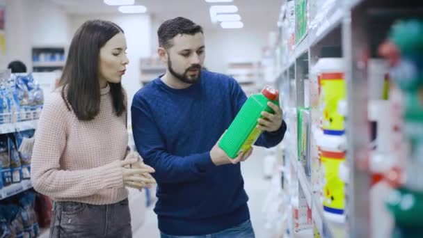 Un tipo y su novia eligen productos de los estantes de un supermercado de construcción . — Vídeo de stock