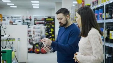 Bir erkek ve bir kadın, bir inşaat süpermarketinde gerekli ev eşyalarını arıyorlar..