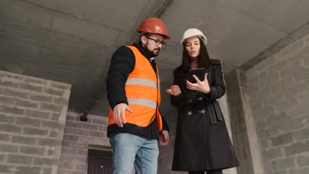 Ingeniera se comunica con el constructor discutiendo los momentos de trabajo de la construcción de un edificio residencial . — Vídeo de stock