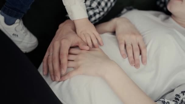 妊娠中の女性の腹部の背景に夫と小さな子供の手 — ストック動画