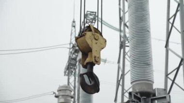 Tower crane lifting hook detail against cloudy sky at construction site.