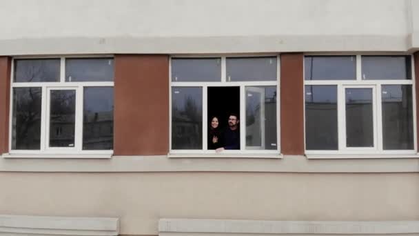 A young couple in a new apartment building admiring the view from the window. — Stok video