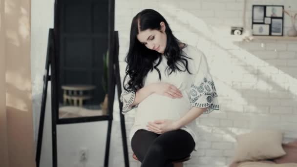 Attractive pregnant brunette runs hands on large belly — Wideo stockowe