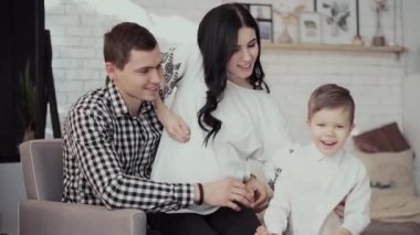 Çocuk uzun saçlı kadına yaklaşır annesi hamile kadını öper.