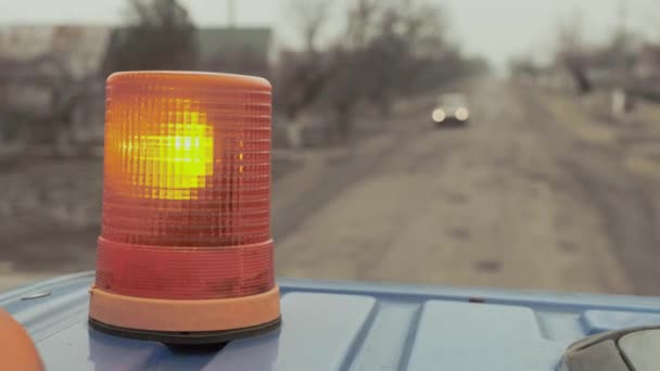 Blinklicht an Spezialgeräten vor dem Hintergrund einer armen Landstraße und fahrender Fahrzeuge. — Stockvideo