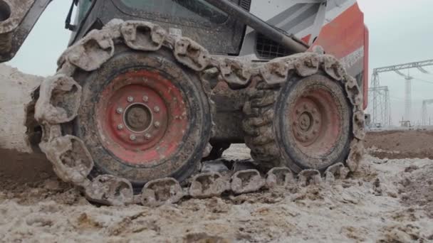 A kerekeken hernyókkal felszerelt kis traktor ásatási munkákat végez — Stock videók