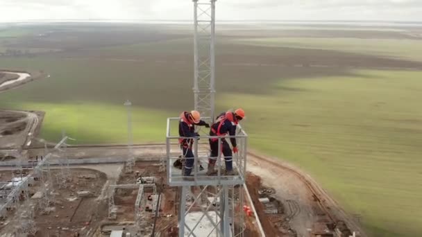 Electricistas tiran de alambre en la torre de transmisión de energía aérea — Vídeos de Stock