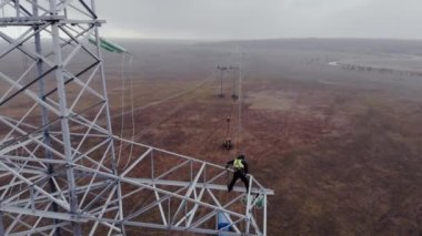 Adam güç iletim kulesinde çalışıyor.