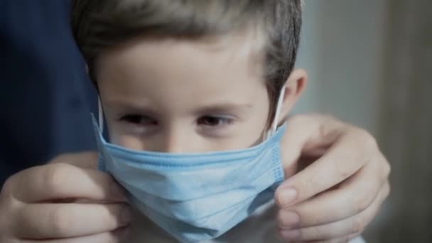 A man puts a medical mask on a boy — Stock Video