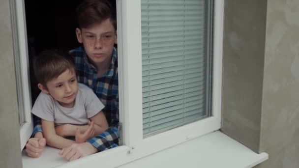 Kinder während der Quarantäne schauen mit mattem Blick aus dem Fenster. — Stockvideo