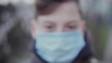 13 yaşında, tıbbi maskeli bir genç..