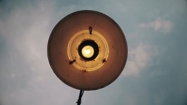 Lámpara vieja con una bombilla sobre un fondo de cielo gris otoñal . — Vídeo de stock