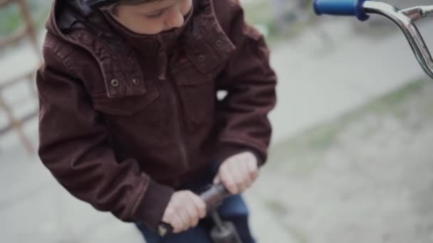 Un niño de 5 años sacude las ruedas de una bicicleta infantil con una bomba de coche — Vídeos de Stock