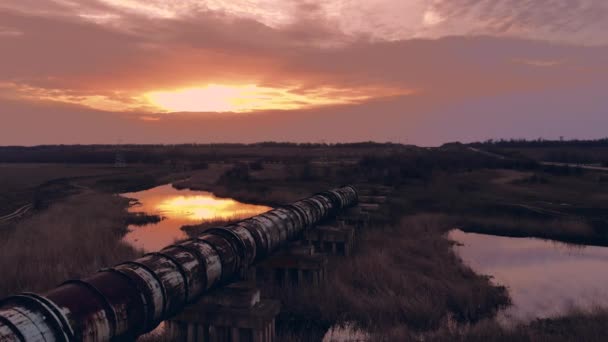 Vista apocalíptica de un río pantanoso y una tubería de metal contra el sol poniente — Vídeos de Stock