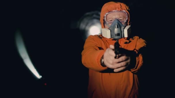 Ein Mann mit Atemschutzmaske zückt in einem Unterstand eine Waffe und zielt in die Kamera — Stockvideo