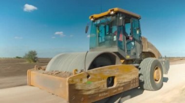 Hızlandırılmış atışta asfalt ve toprağı sıkıştırmak için traktör.