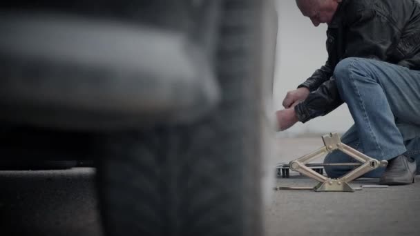 Ein älterer Mann wechselt selbstständig das Rad in seinem Auto mitten auf der Autobahn — Stockvideo