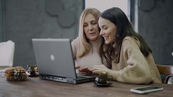 Uma filha ensina sua mãe a usar um laptop para compras on-line . — Vídeo de Stock