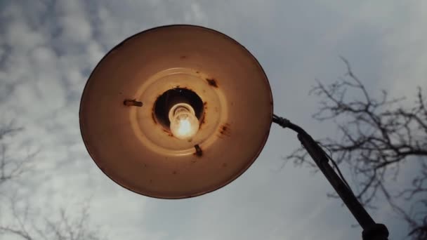 Stará a rezavá pouliční lampa houpající se ve větru proti ponuré šedé obloze. — Stock video