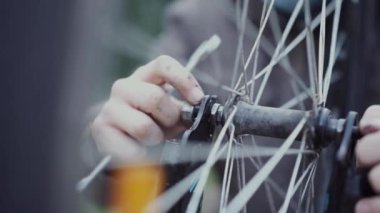 Bir genç bisikletinin tekerleğini tamir ediyor.