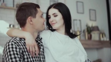 Kareli gömlekli adam, güzel hamile esmer kadına sarılıyor.