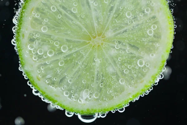 Lime slice falling into water Royalty Free Stock Images