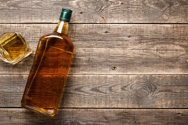 Fles en glas whisky op houten planken — Stockfoto