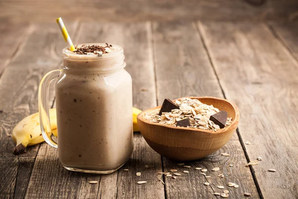 Frullato di cioccolato alla banana e muesli sul tavolo di legno — Foto Stock