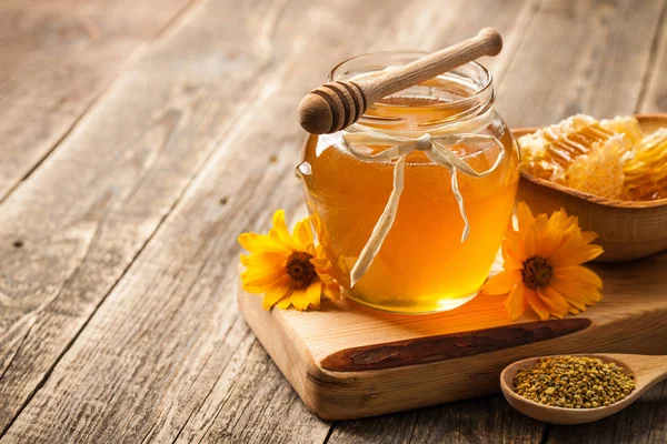 Honey in glass jar and honeycomb on wooden table — Stock Photo, Image