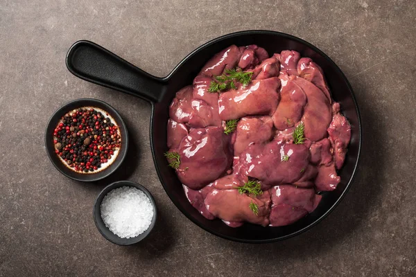 Fígado cru de frango na frigideira, sal e pimenta na mesa da cozinha — Fotografia de Stock