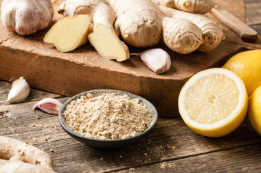 Zencefil kökü, zencefil tozu, sarımsak ve ahşap masada taze limon.
